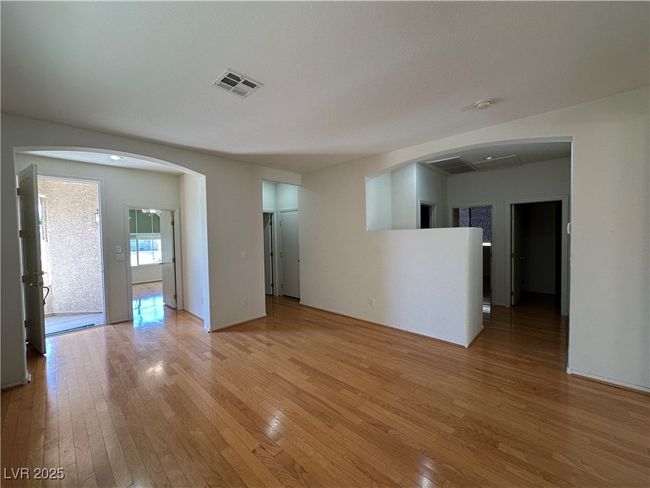 Empty room with light wood-style floors and arched walkways | Image 4
