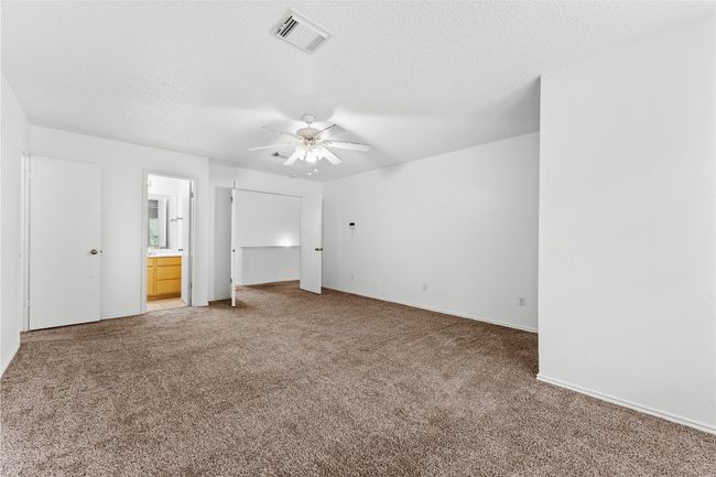 Unfurnished bedroom featuring light colored carpet, connected bathroom, a textured ceiling, baseboards, and ceiling fan | Image 24