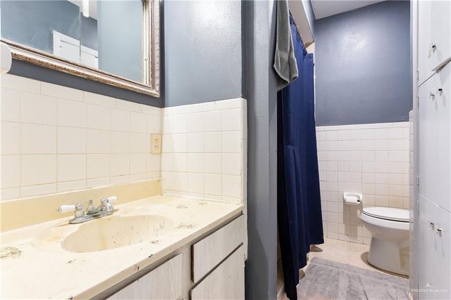 Bathroom with tile walls, wainscoting, vanity, and curtained shower | Image 8