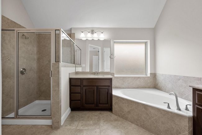Bathroom featuring vanity, a garden tub, a stall shower, and tile patterned flooring | Image 15