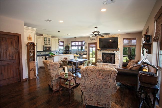 Living room with a ceiling fan, dark wood-style floors, plenty of natural light, a stone fireplace, and recessed lighting | Image 21