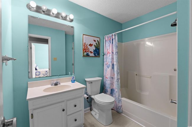 Bathroom featuring toilet, vanity, shower / bath combination with curtain, and a textured ceiling | Image 21