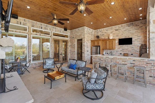 Natural stonetravertine, in a "Versailles" pattern, covers the floors with Old Chicago Brickwalls. The ceiling is stained wood planks with 2 Craftmade 70" outdoor ceiling fans with walnut hand-scraped blades and aged bronze metalaccents and seeded glass light fixtures. | Image 38