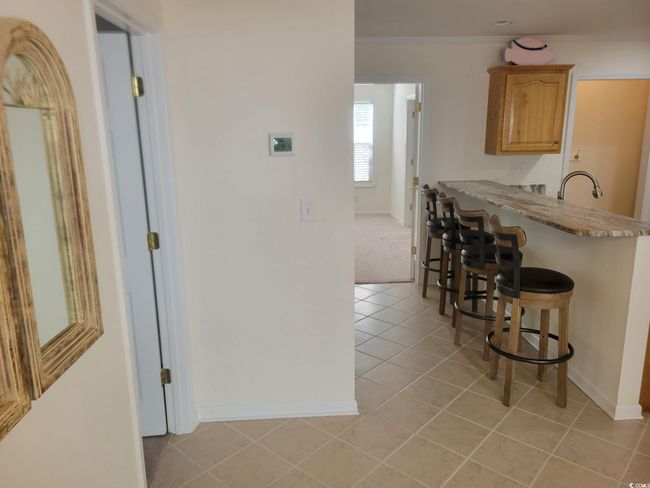 Kitchen with a breakfast bar area, light tile patterned floors, ornamental molding, and a peninsula | Image 7