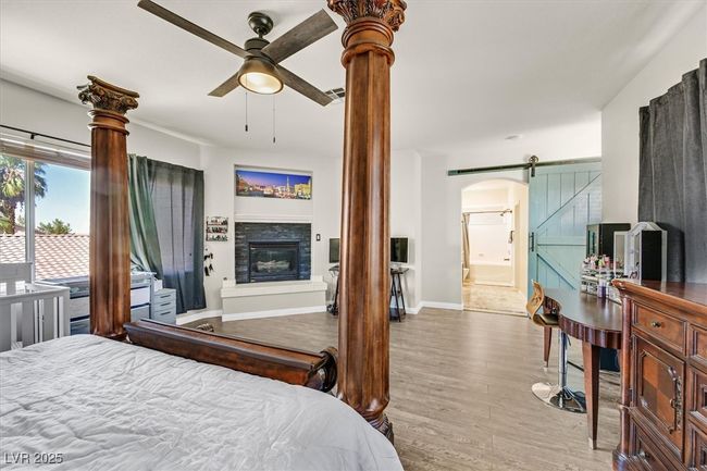 Bedroom with baseboards, a barn door, wood finished floors, arched walkways, and a glass covered fireplace | Image 17