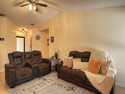 Living room featuring a textured ceiling, light tile patterned floors, lofted ceiling, and ceiling fan | Image 3