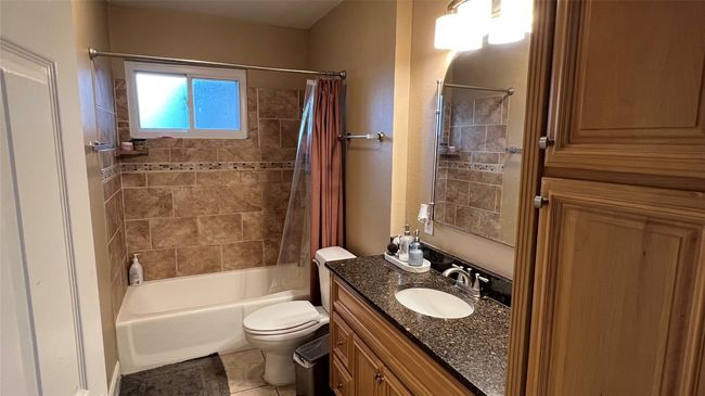 Bathroom with vanity, shower / tub combo with curtain, toilet, and tile patterned flooring | Image 16