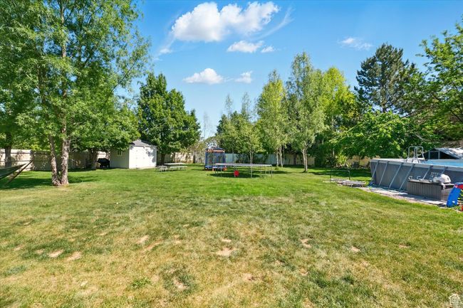 View of yard featuring a trampoline and an outdoor pool | Image 30