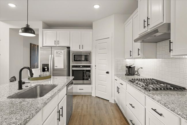 Kitchen with appliances with stainless steel finishes, under cabinet range hood, white cabinets, recessed lighting, and pendant lighting | Image 21