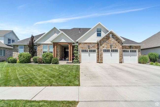 View of front facade featuring stone siding, driveway, a front lawn, and a garage | Image 79