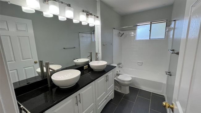 Bathroom featuring tile patterned floors, toilet, shower combination, and double vanity | Image 8