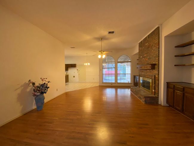 Unfurnished living room featuring wood finished floors, a brick fireplace, and ceiling fan | Image 8