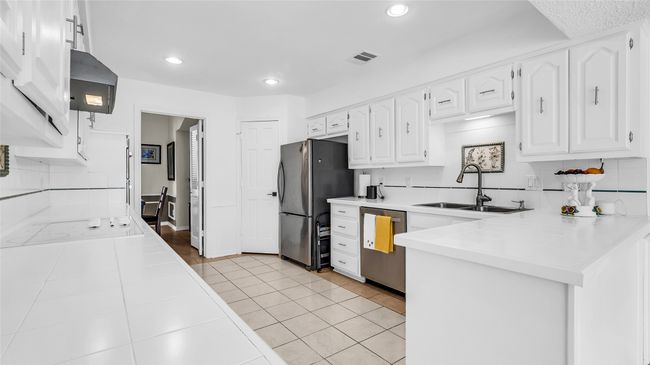 Kitchen with appliances with stainless steel finishes, white cabinetry, a peninsula, tasteful backsplash, and extractor fan | Image 7
