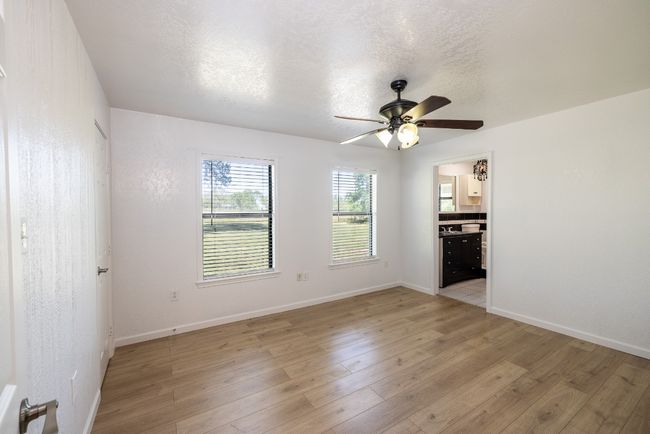 Empty room featuring light wood-style flooring, a textured ceiling, baseboards, and a ceiling fan | Image 13