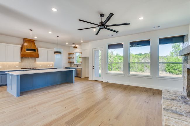 Kitchen featuring custom exhaust hood, light countertops, ceiling fan, a wealth of natural light, and white cabinetry | Image 7