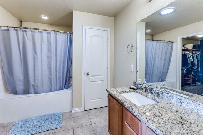 Bathroom with vanity, shower / tub combo with curtain, tile patterned floors, and a walk in closet | Image 34