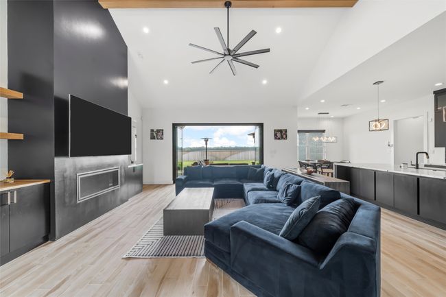 Living area featuring a fireplace, light wood-style floors, a ceiling fan, and high vaulted ceiling | Image 10
