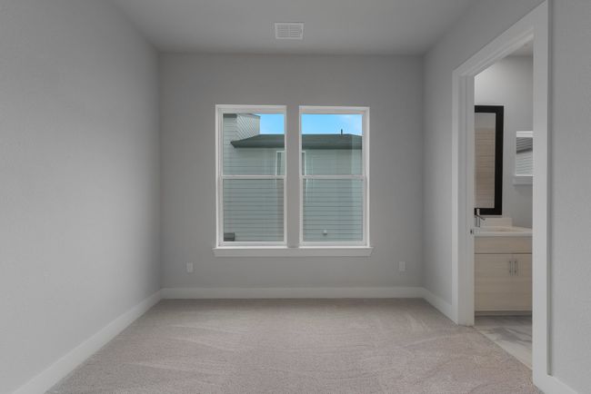 Unfurnished bedroom featuring light colored carpet, baseboards, connected bathroom, and visible vents | Image 18