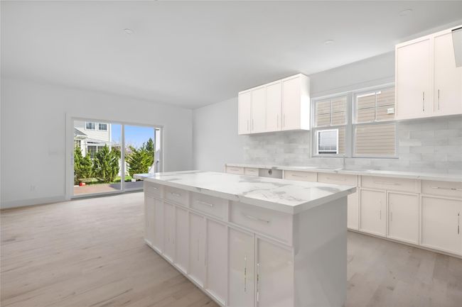 Kitchen featuring backsplash, a center island, white cabinetry, and light wood-style flooring | Image 6
