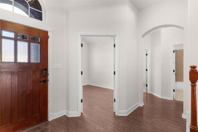 Entrance foyer featuring a high ceiling, dark wood-style floors, arched walkways, and baseboards | Image 4