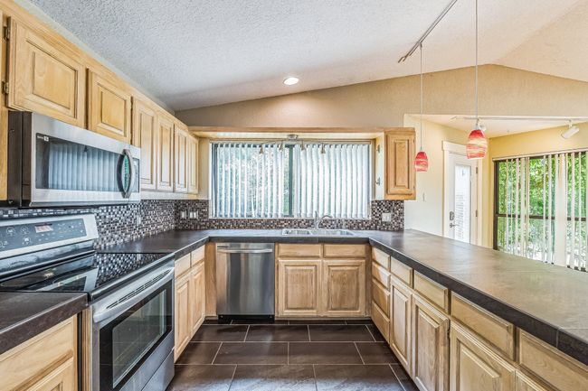 Kitchen with appliances with stainless steel finishes, decorative backsplash, lofted ceiling, and a sink | Image 15