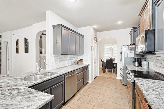 Kitchen featuring appliances with stainless steel finishes, arched walkways, light stone counters, tasteful backsplash, and recessed lighting | Image 11