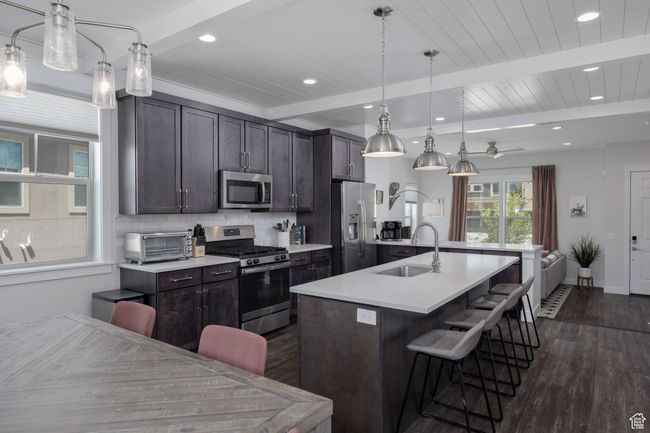 Kitchen featuring stainless steel appliances, dark wood-type flooring, a sink, a kitchen island with sink, and a breakfast bar area | Image 13