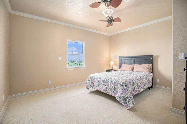 This oversized secondary bedroom, situated conveniently at the top of the stairs, offers a remarkable sense of spaciousness. The generous dimensions provide ample room for a variety of furniture arrangements, creating a comfortable and versatile living area. Adding a touch of elegance, refined crown molding gracefully accents the perimeter of the room, enhancing its overall aesthetic appeal. | Image 23