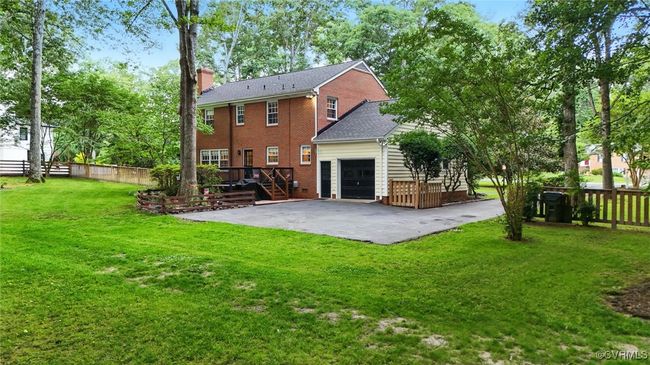Back of house with a chimney, brick siding, a deck, a garage, and stairway | Image 7