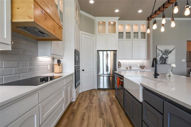 Kitchen featuring appliances with stainless steel finishes, crown molding, white cabinets, and custom range hood | Image 5