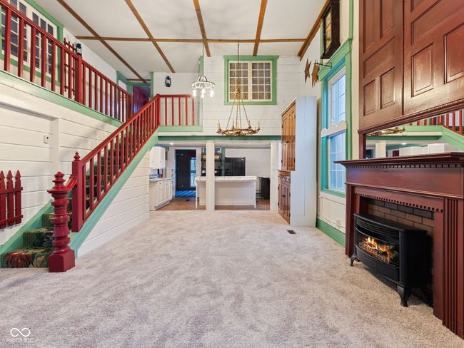 unfurnished living room with carpet flooring, a high ceiling, stairs, and wooden walls | Image 9
