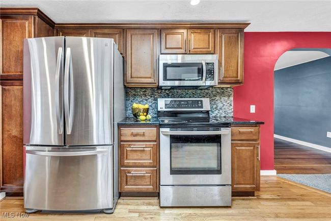 Kitchen featuring appliances with stainless steel finishes, a skylight, radiator heating unit, light wood flooring, and maple cabinetry | Image 8