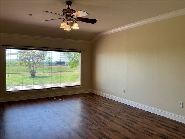 Empty room featuring a ceiling fan, baseboards, ornamental molding, and dark wood-style flooring | Image 11