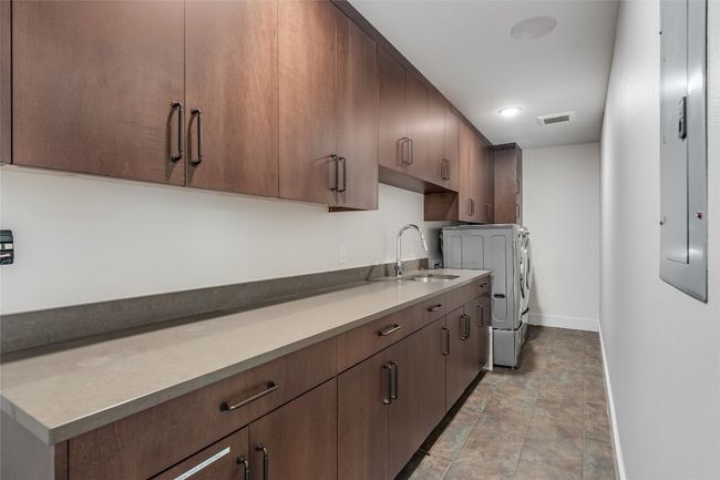 The large laundry room has tons of storage, a convenient sink, and ample counter space. | Image 22