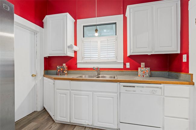 Kitchen with dishwasher, white cabinetry, light wood-type flooring, freestanding refrigerator, and decorative light fixtures | Image 14
