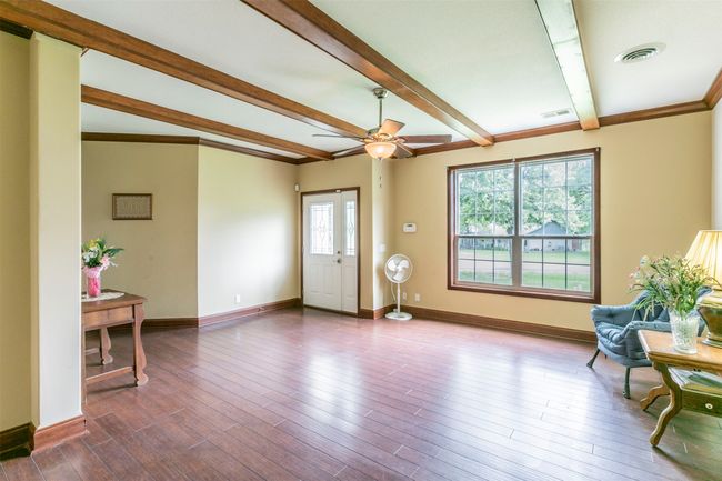 Foyer featuring visible vents, beamed ceiling, baseboards, dark wood-type flooring, and a ceiling fan | Image 9