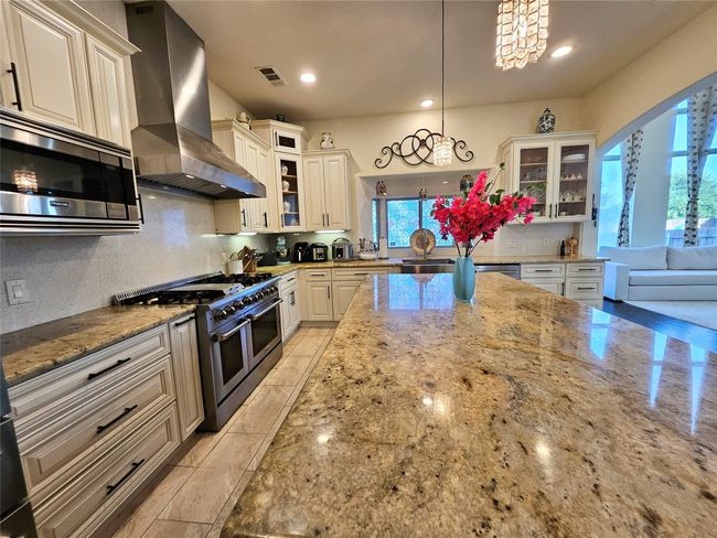 Kitchen with appliances with stainless steel finishes, island exhaust hood, a chandelier, light stone countertops, and recessed lighting | Image 16