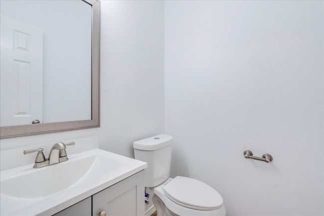 The half bath, conveniently located off the kitchen, has been updated with a new vanity cabinet and sink, modern faucets, a new mirror, toilet, towel bar, and towel ring. | Image 9