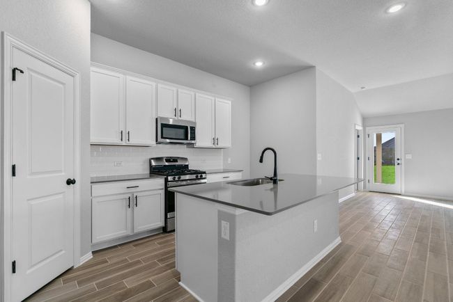 Kitchen with tasteful backsplash, a sink, wood finished floors, a center island with sink, and stainless steel appliances | Image 8