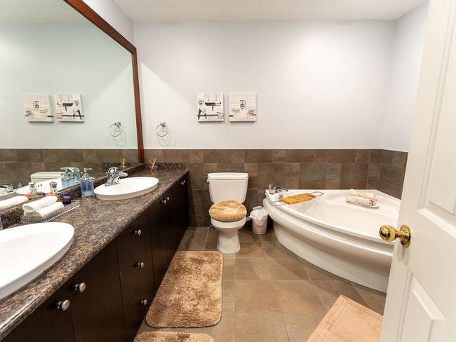 Full bath with toilet, a sink, tile walls, and a bath | Image 25