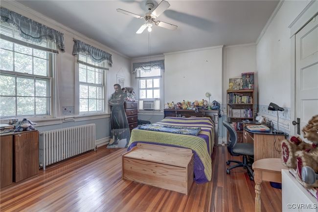 Bedroom with ceiling fan, crown molding, wood finished floors, and radiator heating unit | Image 20