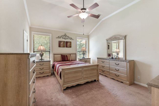 Bedroom with crown molding, lofted ceiling, light colored carpet, and ceiling fan | Image 26