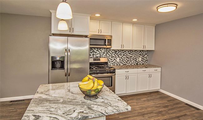 Kitchen featuring stainless steel appliances, white cabinetry, and light stone counters | Image 4