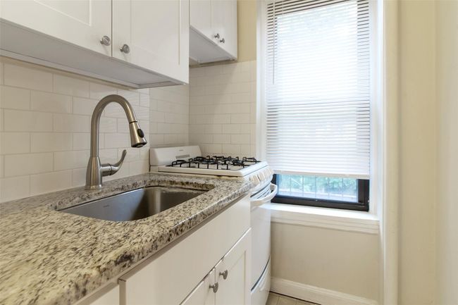Kitchen featuring healthy amount of natural light, white gas stove, backsplash, and white cabinetry | Image 8