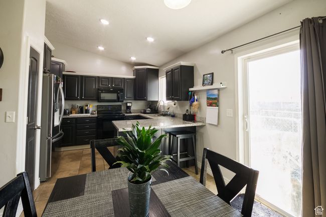 Kitchen with black appliances, a healthy amount of sunlight, and a sink | Image 8