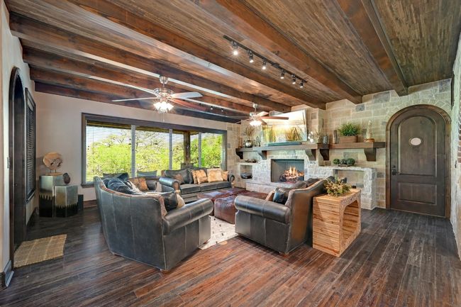 Living room with wooden ceiling, a stone fireplace, ceiling fan, dark wood-type flooring, and rail lighting | Image 15