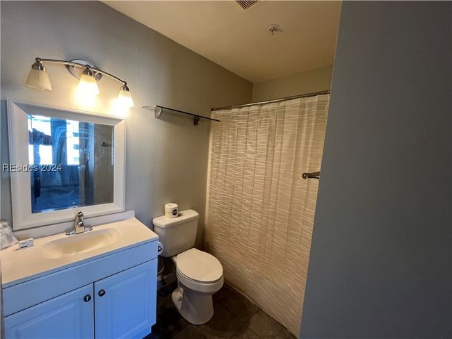 Bathroom featuring toilet, curtained shower, vanity, and tile patterned flooring | Image 13