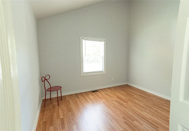 Empty room featuring light wood finished floors and vaulted ceiling | Image 6