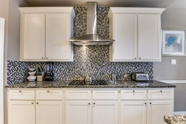 Kitchen with white cabinets, tasteful backsplash, and wall chimney range hood | Image 20