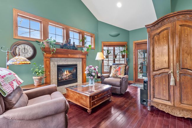 Primary bedroom suite with fireplace, mahogany hardwood floors, extra high ceilings, view to back yard and woods. Door to full length covered deck. | Image 22